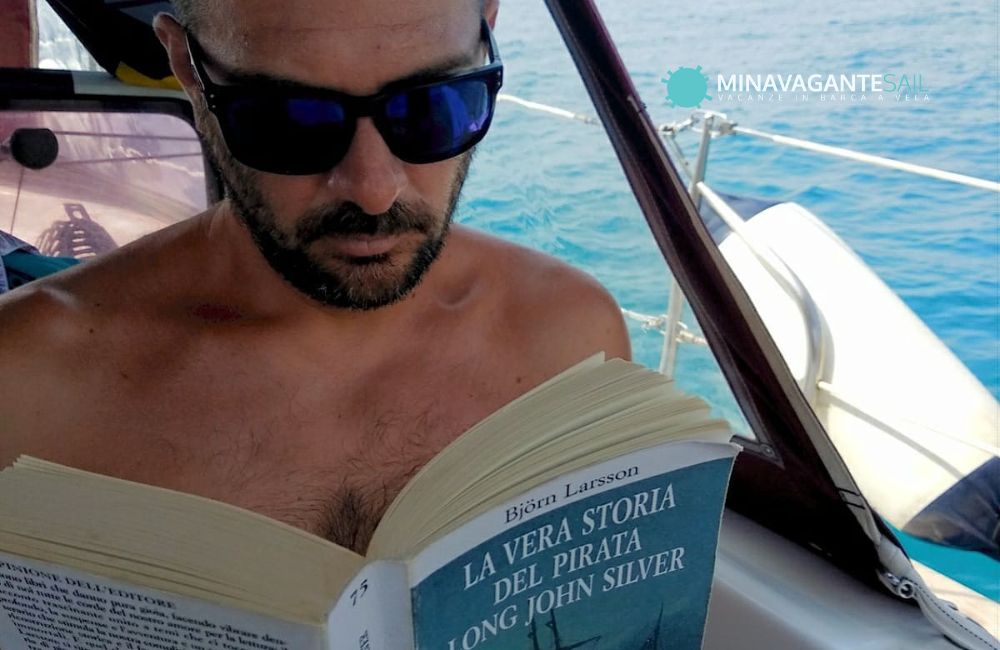 Foto di Andrea in barca che legge il libro “la vera storia del pirata Long John Silver”, uno dei più bei libri di mare