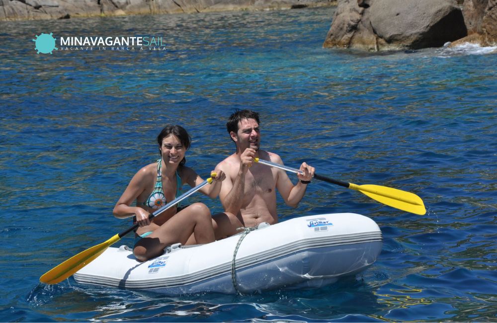 Alice e Andrea che navigano a remi su un gommone durante una vacanza in barca a vela in Toscana
